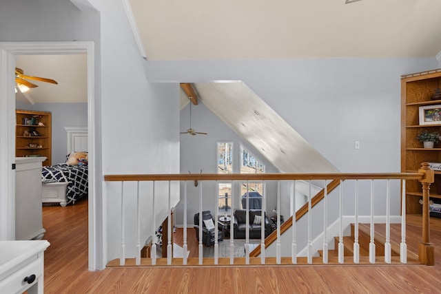 staircase featuring a ceiling fan, vaulted ceiling with beams, baseboards, and wood finished floors