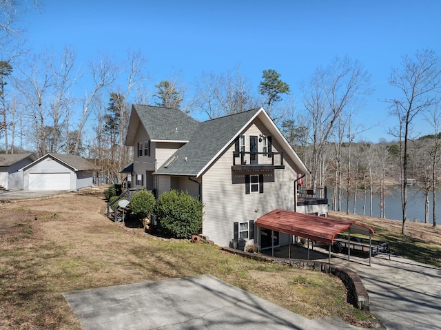 view of side of home featuring an outbuilding, roof with shingles, a yard, and a balcony