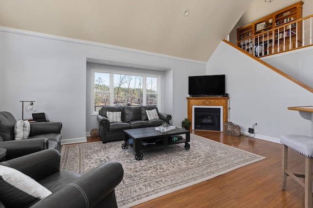 living area with high vaulted ceiling, a fireplace, wood finished floors, and baseboards