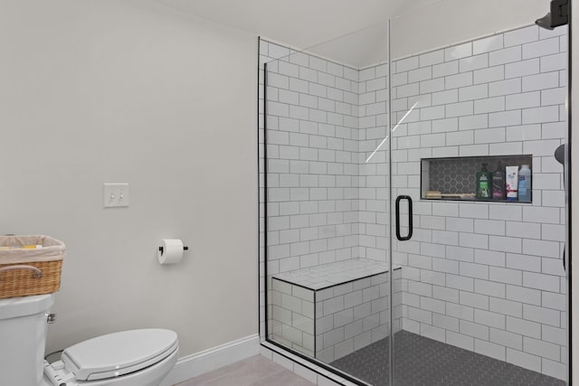 full bath featuring toilet, a shower stall, and baseboards