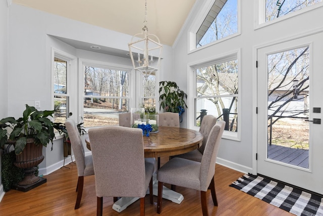 dining space featuring high vaulted ceiling, baseboards, and wood finished floors