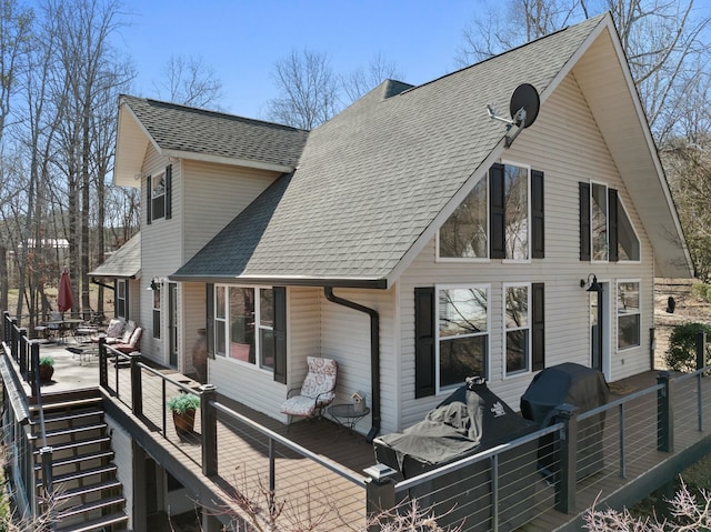 back of property featuring a deck, a shingled roof, and stairs