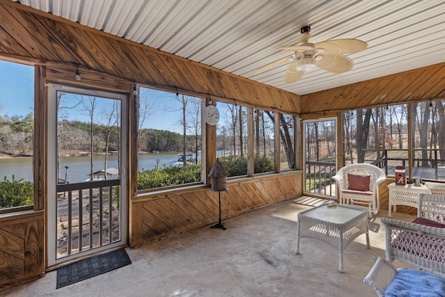 unfurnished sunroom with a healthy amount of sunlight, a water view, and ceiling fan