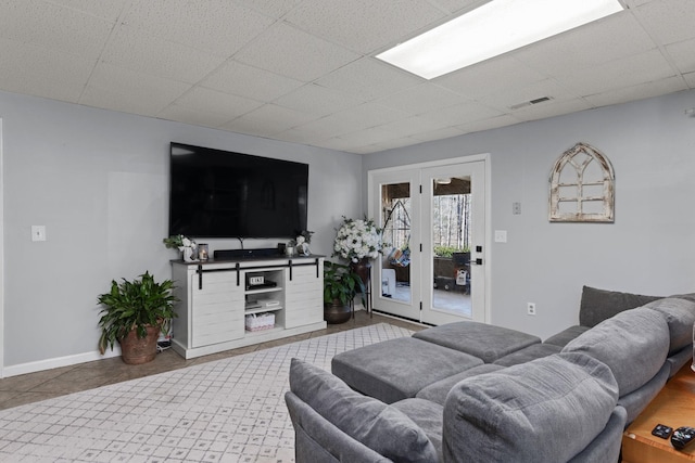 tiled living area with a paneled ceiling, visible vents, and baseboards