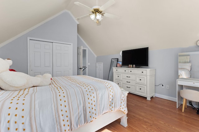 bedroom featuring baseboards, lofted ceiling, light wood-style flooring, ceiling fan, and a closet