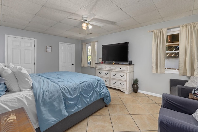 bedroom with a paneled ceiling, ceiling fan, baseboards, and light tile patterned flooring