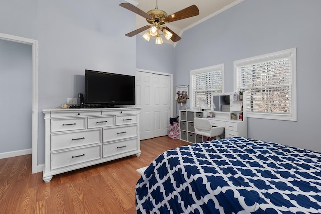 bedroom with crown molding, a closet, ceiling fan, wood finished floors, and baseboards