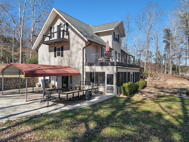 back of property featuring a shingled roof, a lawn, a balcony, a sunroom, and a patio area