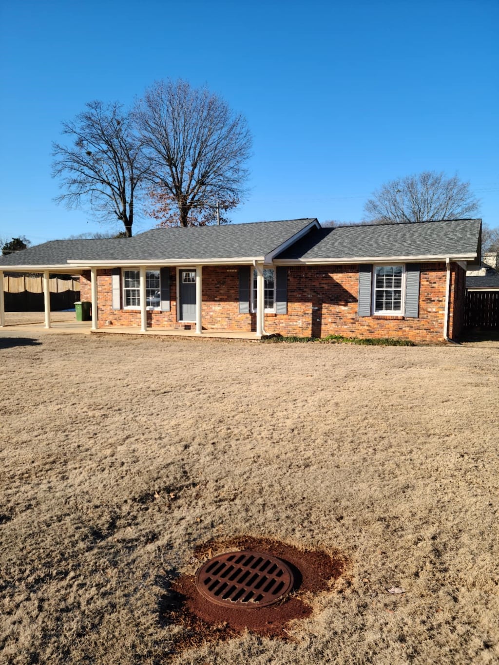 ranch-style home with brick siding, roof with shingles, and a carport