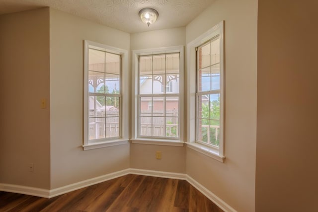 spare room with a textured ceiling and dark wood-type flooring