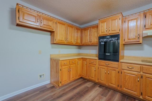 kitchen featuring wood-type flooring, a textured ceiling, and black oven