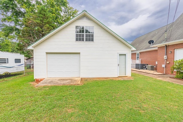 rear view of property featuring central AC, a yard, a garage, and an outdoor structure