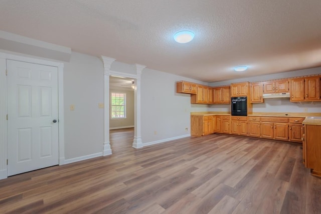 kitchen with black oven, ceiling fan, a textured ceiling, and light wood-type flooring