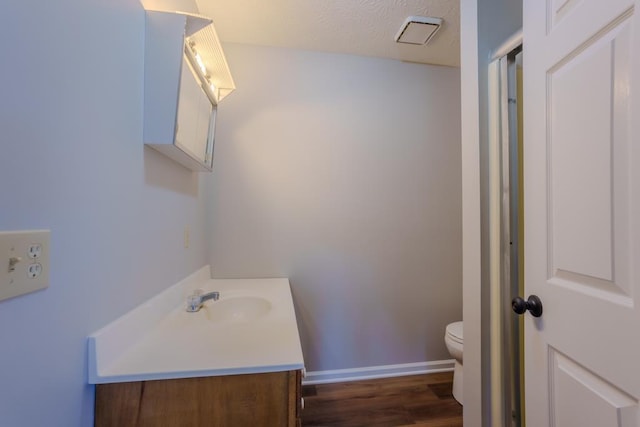 bathroom with hardwood / wood-style flooring, vanity, toilet, and a textured ceiling