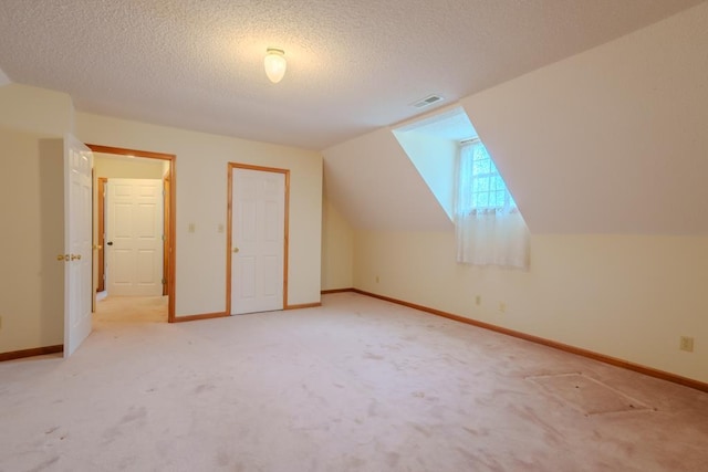 additional living space featuring light colored carpet, lofted ceiling, and a textured ceiling