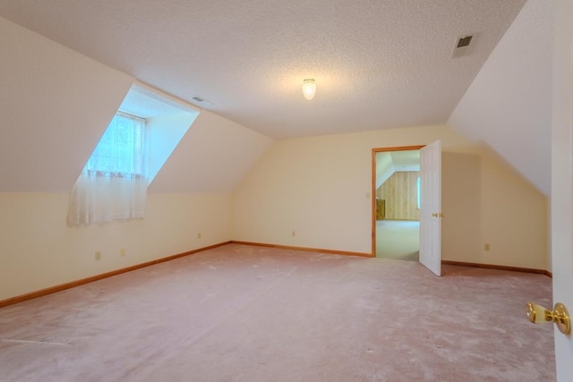 bonus room with lofted ceiling, a textured ceiling, and light carpet