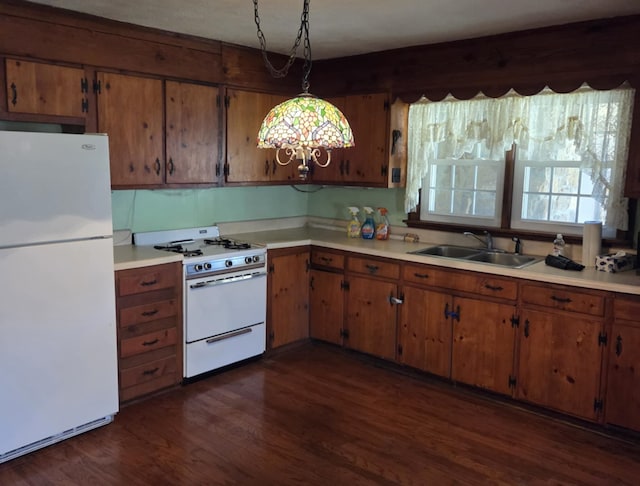 kitchen featuring white appliances, dark wood-style flooring, light countertops, pendant lighting, and a sink