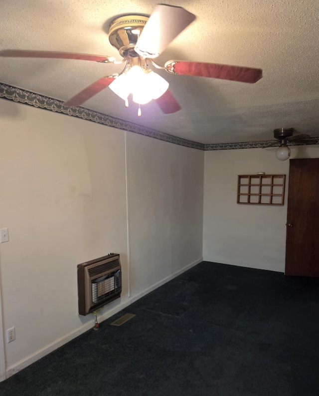 unfurnished room featuring visible vents, a ceiling fan, heating unit, dark colored carpet, and a textured ceiling