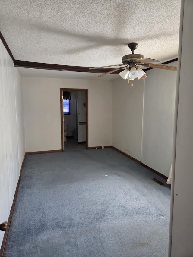 carpeted empty room with ceiling fan, visible vents, baseboards, and a textured ceiling