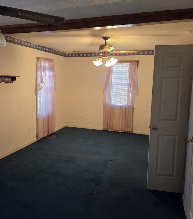 spare room featuring baseboards, visible vents, dark carpet, and ceiling fan