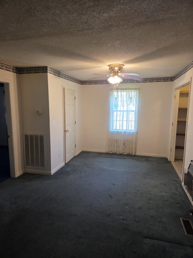 unfurnished bedroom with a textured ceiling, dark carpet, and visible vents