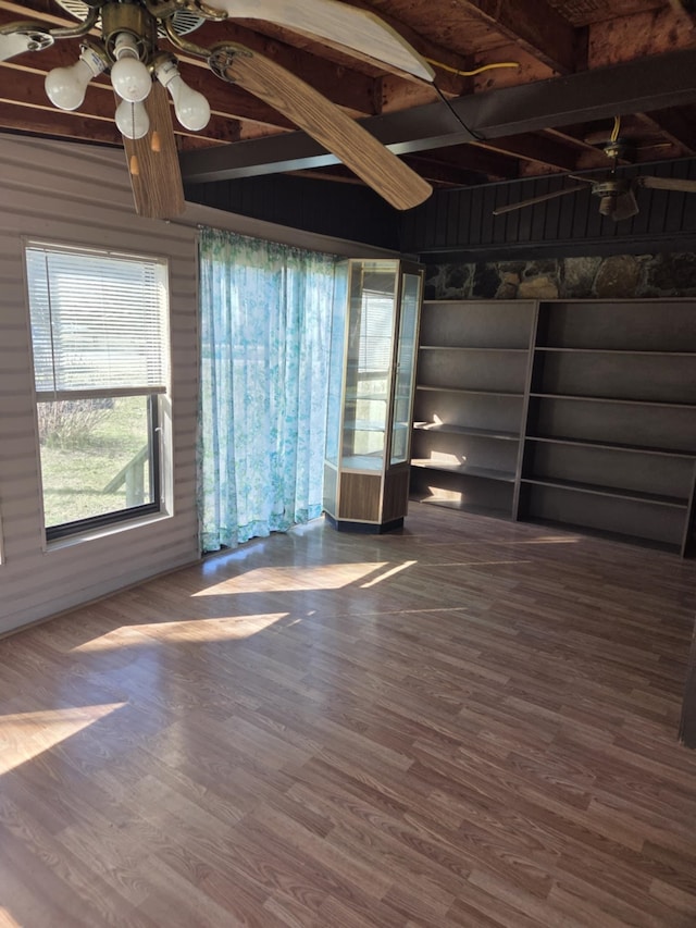 interior space featuring a ceiling fan, beamed ceiling, and wood finished floors