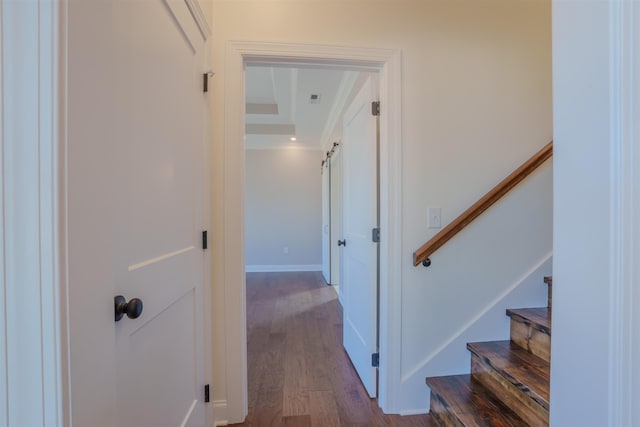 hall featuring dark wood-style floors, visible vents, stairway, a barn door, and baseboards