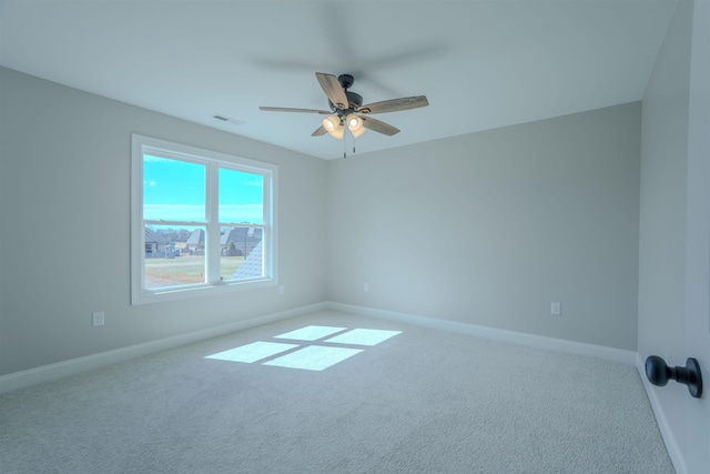 empty room featuring carpet floors, visible vents, ceiling fan, and baseboards