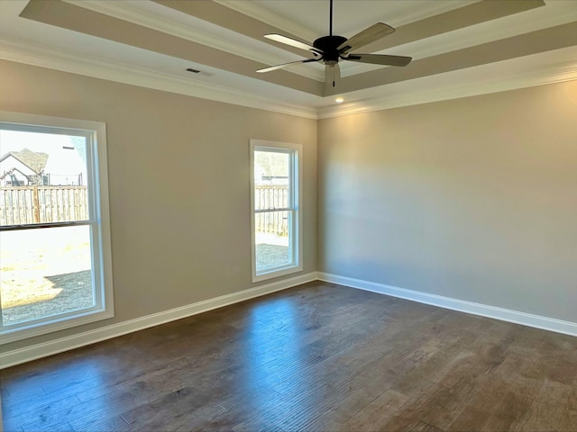 empty room with ornamental molding, dark hardwood / wood-style floors, ceiling fan, and a tray ceiling