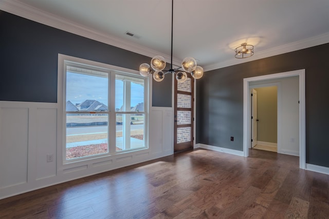 spare room with dark wood-style flooring, a notable chandelier, visible vents, a decorative wall, and ornamental molding