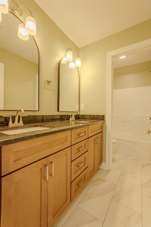 full bath featuring marble finish floor, a sink, toilet, and double vanity