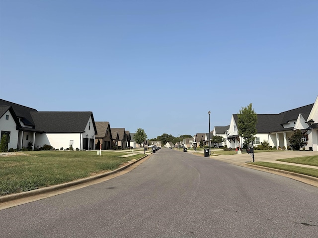 view of street featuring curbs, street lighting, sidewalks, and a residential view