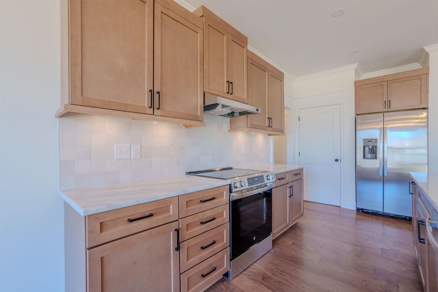 kitchen with under cabinet range hood, wood finished floors, appliances with stainless steel finishes, backsplash, and crown molding