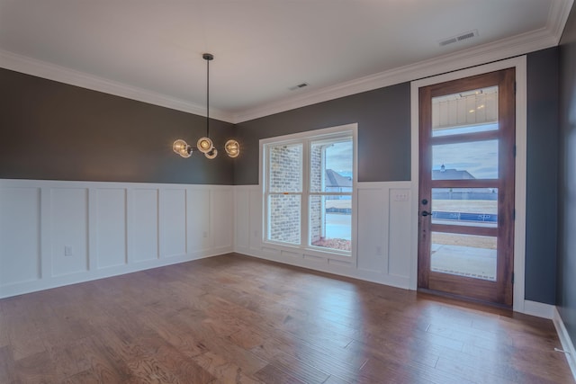 empty room with ornamental molding, wood finished floors, and visible vents