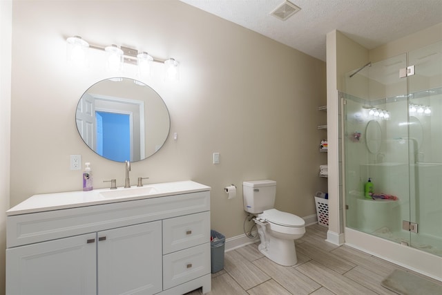  - bathroom featuring vanity, a shower stall, wood finish floors, and a textured ceiling