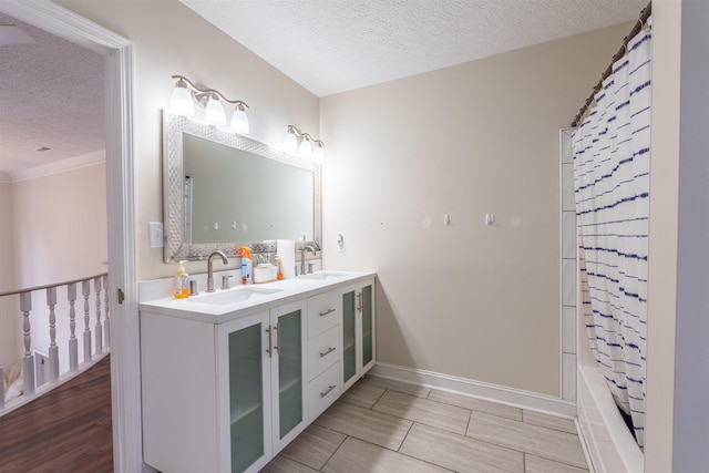 - bathroom featuring a textured ceiling, double vanity, wood finished floors, shower / tub combo with curtain, and crown molding
