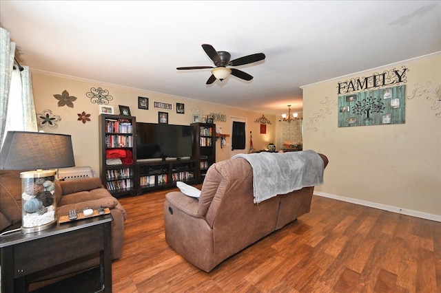 living room featuring hardwood / wood-style flooring, ceiling fan with notable chandelier, and crown molding