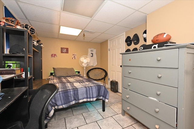 bedroom with a paneled ceiling and light tile patterned floors