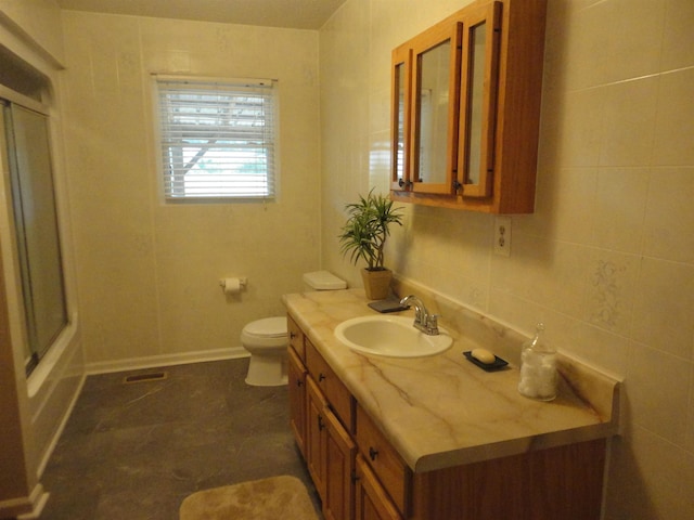 full bathroom featuring decorative backsplash, vanity, shower / bath combination with glass door, tile walls, and toilet