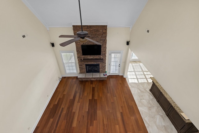 unfurnished living room featuring ceiling fan, wood-type flooring, a fireplace, and a wealth of natural light