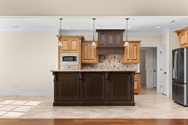 kitchen with light stone countertops, appliances with stainless steel finishes, hanging light fixtures, and an island with sink