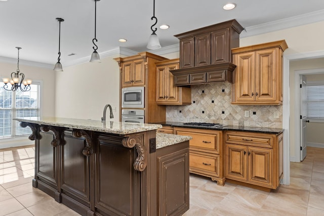 kitchen featuring pendant lighting, stainless steel appliances, a center island with sink, and an inviting chandelier