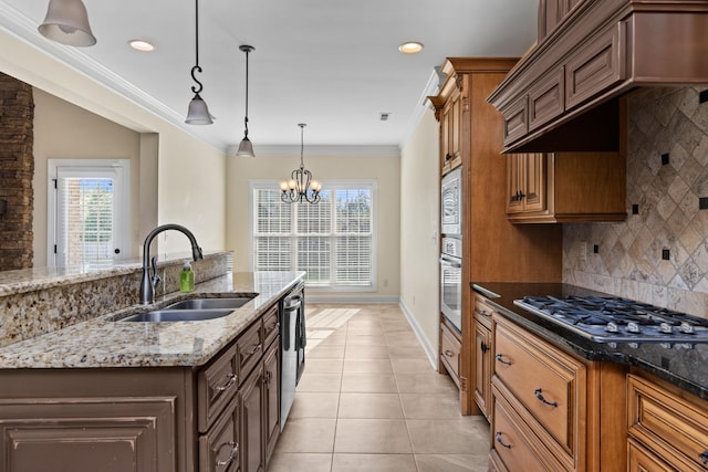 kitchen featuring backsplash, sink, light stone countertops, appliances with stainless steel finishes, and a notable chandelier