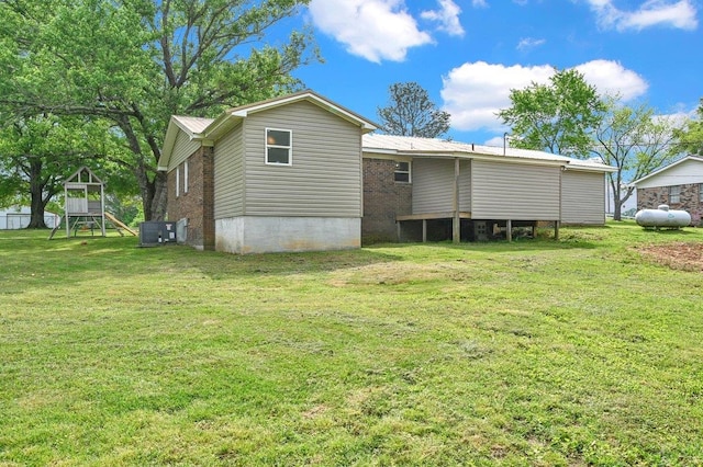 back of house with a lawn, central AC unit, and a playground