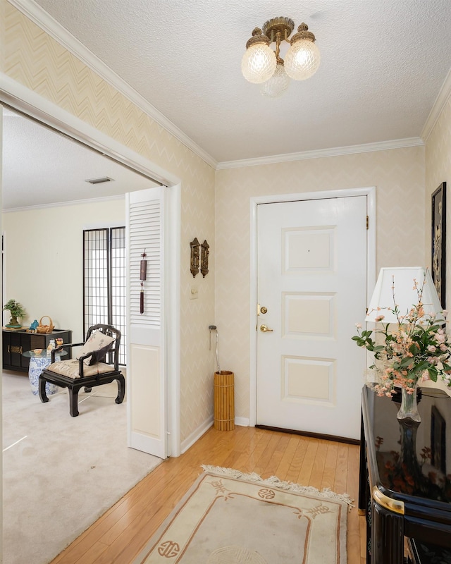 entryway with wood-type flooring, crown molding, and a textured ceiling