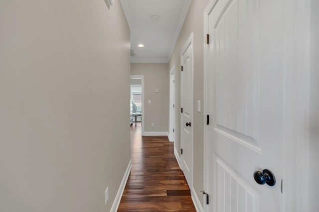 hallway with dark wood-type flooring, recessed lighting, ornamental molding, and baseboards