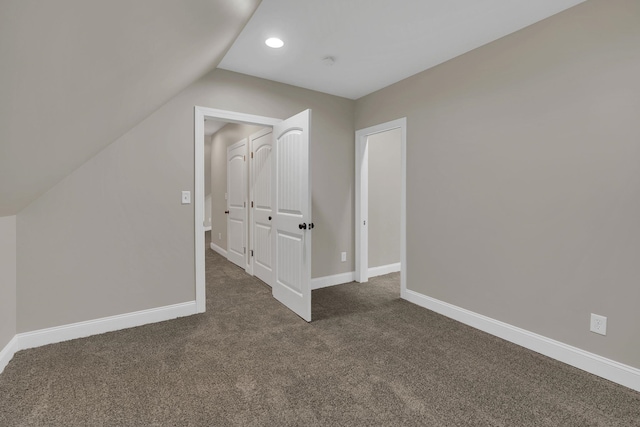 additional living space featuring lofted ceiling, baseboards, and dark colored carpet