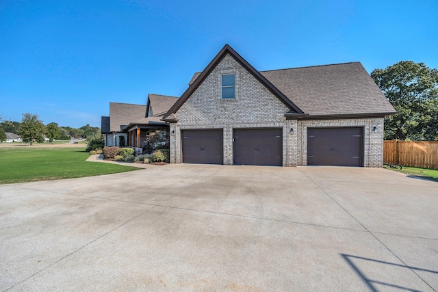 view of front of property featuring brick siding, concrete driveway, roof with shingles, fence, and a front yard