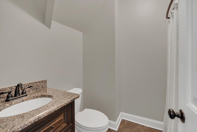 bathroom featuring baseboards, vanity, and toilet