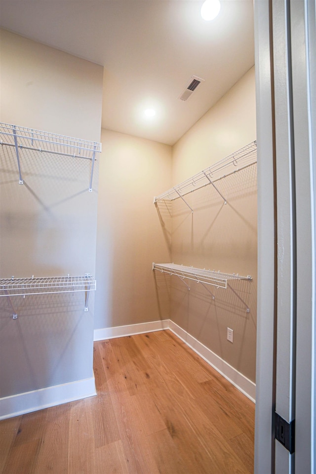 walk in closet with hardwood / wood-style flooring